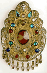 Серебряная брошь из Аттики, отделанная стеклянными имитациями драгоценных камней и носимая поверх цакоса, жилета с короткими рукавами
